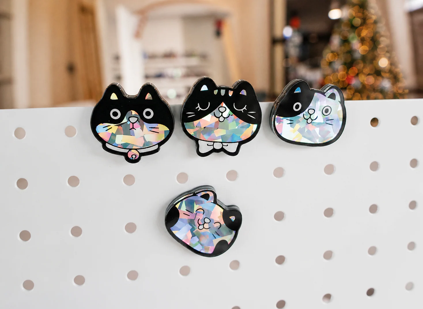 ホログラム加工を入れた猫モチーフのアクリルチャーム展示サンプル。キャラクターグッズOEMの仕上がり確認画像。