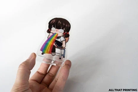 手に持った小型透明アクリルスタンドサンプル。キャラクターアクスタのサイズ感と台座仕様を確認する画像。
